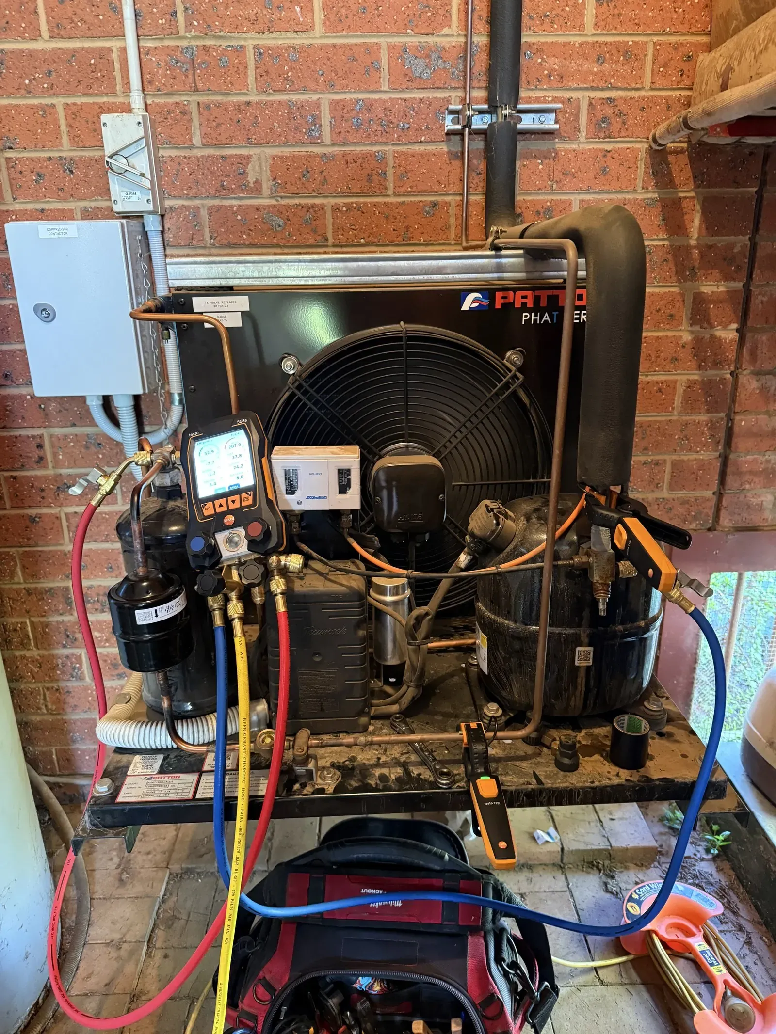 Commercial refrigeration condensing unit under service with refrigerant gauges connected